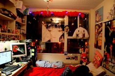 a bedroom decorated for halloween with decorations hanging from the ceiling and two computer desks