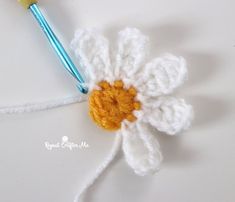 a crocheted flower with a paintbrush in it sitting on a white surface