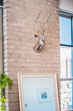 a deer head mounted to the side of a brick wall next to a framed photograph