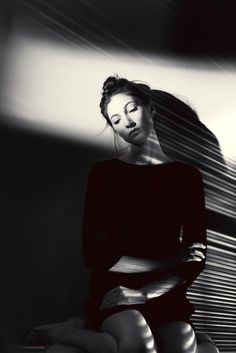 black and white photograph of woman sitting on the floor with her head tilted to the side