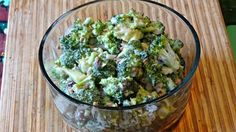 a glass bowl filled with broccoli on top of a wooden table