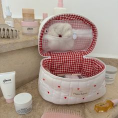 a white teddy bear in a red and white checkered case next to personal care items