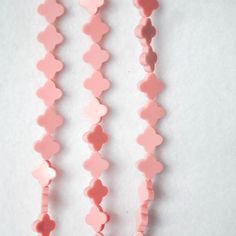 three pink necklaces with hearts hanging from them on a white surface, one in the shape of a heart