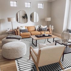 a living room filled with lots of furniture next to a large window on top of a hard wood floor