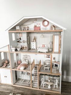 a doll house with furniture and accessories on the floor in front of a white wall