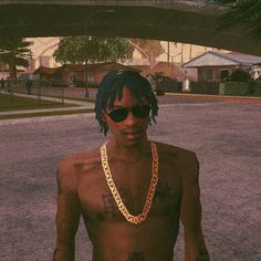 a man with no shirt wearing sunglasses and a gold chain around his neck is standing in the street