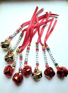 a group of red and gold bell ornaments on a white surface with ribbon around them