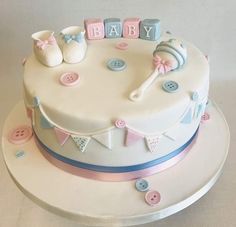 a baby shower cake is decorated with pink, blue and white decorations on a plate