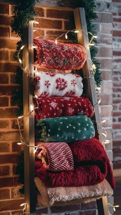 an old ladder is decorated with christmas sweaters and lights for the holiday season in front of a brick wall