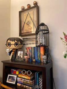 a shelf with books, pictures and a birdcage