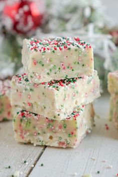 three pieces of white chocolate with sprinkles and christmas decorations in the background