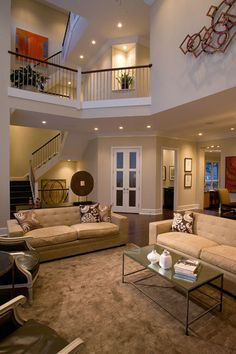 a living room filled with lots of furniture and a stair case in the middle of it