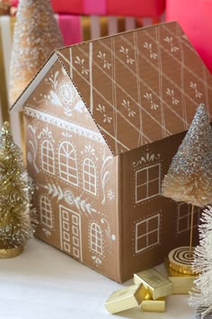 a gingerbread house sitting on top of a table next to christmas trees and presents