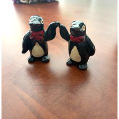 two small black and white figurines sitting on top of a wooden table