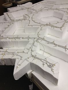 several pieces of white paper are arranged on a table with string lights attached to them