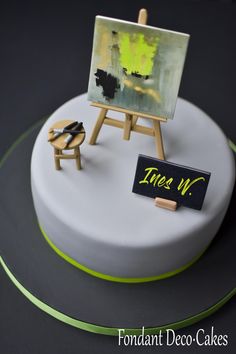 a white cake with an easel and chair on it