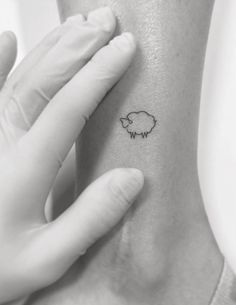 a small sheep tattoo on the back of a woman's left arm and hand