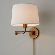 a wall light with a white shade on the side and a beige lamp attached to it