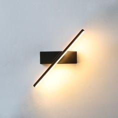 a light that is on the wall next to a white wall with two sticks sticking out of it