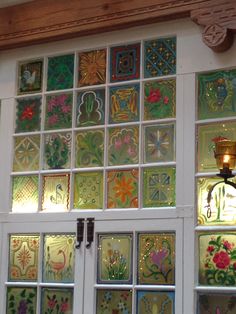 an open door with stained glass panels and a light on the wall above it in front of a window