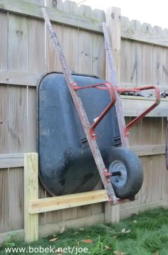 an old suitcase is attached to the back of a cart in a fenced backyard