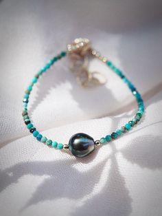 "A boho bracelet beaded to perfection, this adjustable turquoise bracelet flaunts a glowing genuine Tahitian pearl nestled between strands of faceted tiny turquoise beads. ✦ DETAILS ✦ ✧ Name: Ipo (ee POH) - sweetheart, beloved. ✧ Adjustable Length from: 6.5\"-8\". ✧ Genuine 2.5mm faceted tiny Turquoise Beads. ✧ Genuine 8-9mm avg. AA+-AAA Genuine Tahitian Pearl. ✧ 14kt Gold Filled Components, Extender, and Clasp. ✧ All Ke Aloha Jewelry pieces come packaged thoughtfully, beautifully, and ready for Turquoise Single Strand Bracelet As Gift, Turquoise Single Strand Bracelet Gift, Turquoise Single Strand Bracelet For Gift, Elegant Turquoise Bracelets For Beach, Elegant Single Strand Turquoise Bracelet, Tahitian Pearl Bracelet, Hawaii Jewelry, Turquoise Bead Bracelet, Boho Bracelet