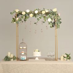 a table topped with a cake next to a birdcage filled with flowers and candles