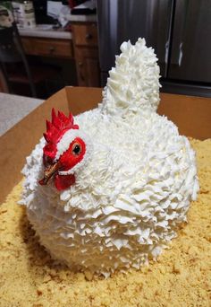 a cake in the shape of a chicken with white frosting on it's head