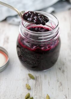 a spoon full of blueberry jam sitting on top of a table