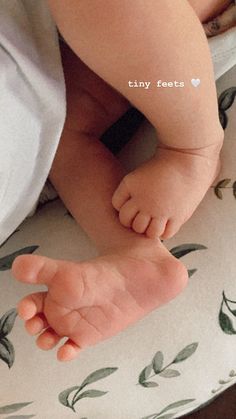 a baby laying on top of a bed next to a teddy bear