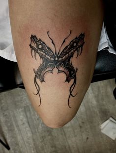 a tattoo on the leg of a woman with an intricate butterfly design in black ink