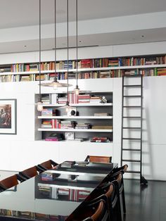 a dining room table with chairs and bookshelves