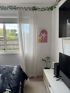 a bed room with a neatly made bed and a flat screen tv