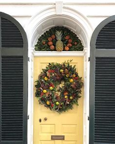 a yellow door with a wreath and pineapples on it