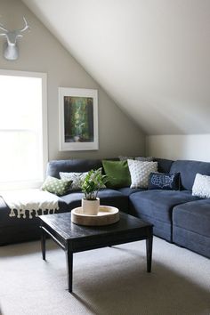 a living room filled with furniture and a painting hanging on the wall above it's windows