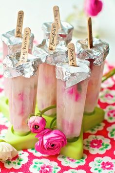 three ice cream sundaes with pink flowers on a table