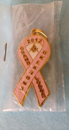 This is a Breast Cancer Awareness Pink Ribbon Oklahoma Masonic Grand Lodge Pendant Lapel Hat Tie Pin Souvenir.  It is versatile as a pendant or a pin with a magnetic back.  It is in its original packaging and therefore in excellent condition. It measures approximately 1-3/8 inches in length and about 5/8 inches wide.   **As with anything that is pre-owned or previously used, there may be some signs of age or use. Most of the pins or other items listed are pre-owned or used. When I state that the Grand Lodge, Aqua Beads, Tie Pin, Buttons Pinback, Aging Signs, Oklahoma, Perfect Gift