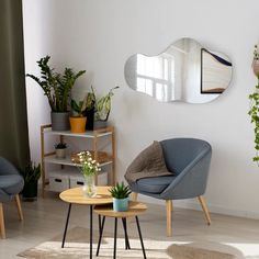 a living room with two chairs and a coffee table in front of a mirror on the wall