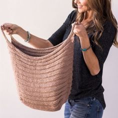 a woman holding up a crocheted shawl in front of a white wall