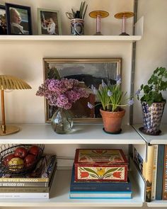 the shelves are filled with books and vases full of flowers, plants, and other decorative items