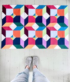 a person standing in front of a colorful quilt