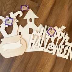 a wooden cut out of the word happy halloween on a wood floor with some decorations