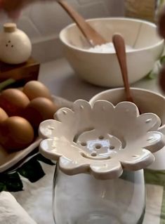 a table topped with bowls filled with eggs and other food items next to utensils