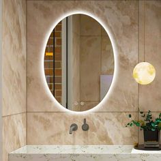 a bathroom sink with a round mirror on the wall above it and a potted plant next to it