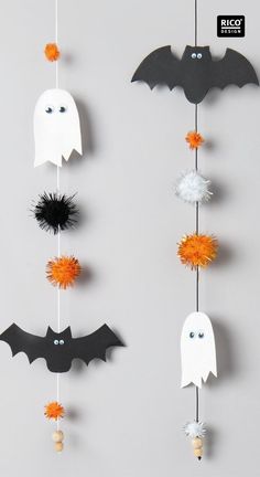 halloween decorations with bats and ghost heads hanging from the strings, on a gray background