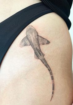 a woman's stomach with a tattoo of a shark on the back of her belly