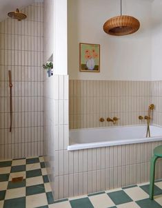 a bath tub sitting next to a green chair in a bathroom with checkered flooring