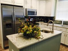 a kitchen with white cabinets and granite counter tops, stainless steel refrigerator and dishwasher