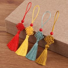 four tassels are sitting on a table next to a brown box with a red bead in the middle