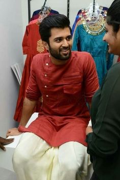 a man in a red shirt and white pants talking to another person